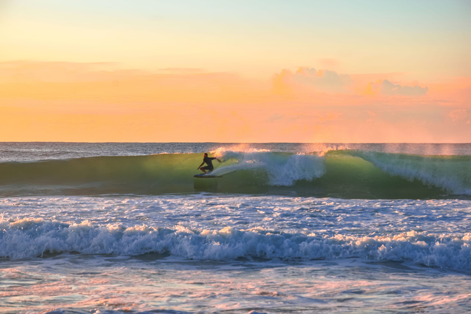 Un surfista solitario pagaia verso il reef vuoto all'alba vicino a Nemberala, Rote